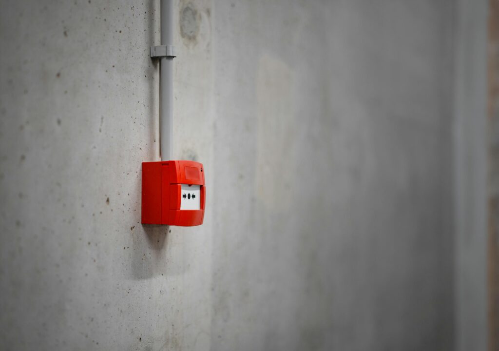 A red alarm box mounted on a gray concrete wall, offering urban security.